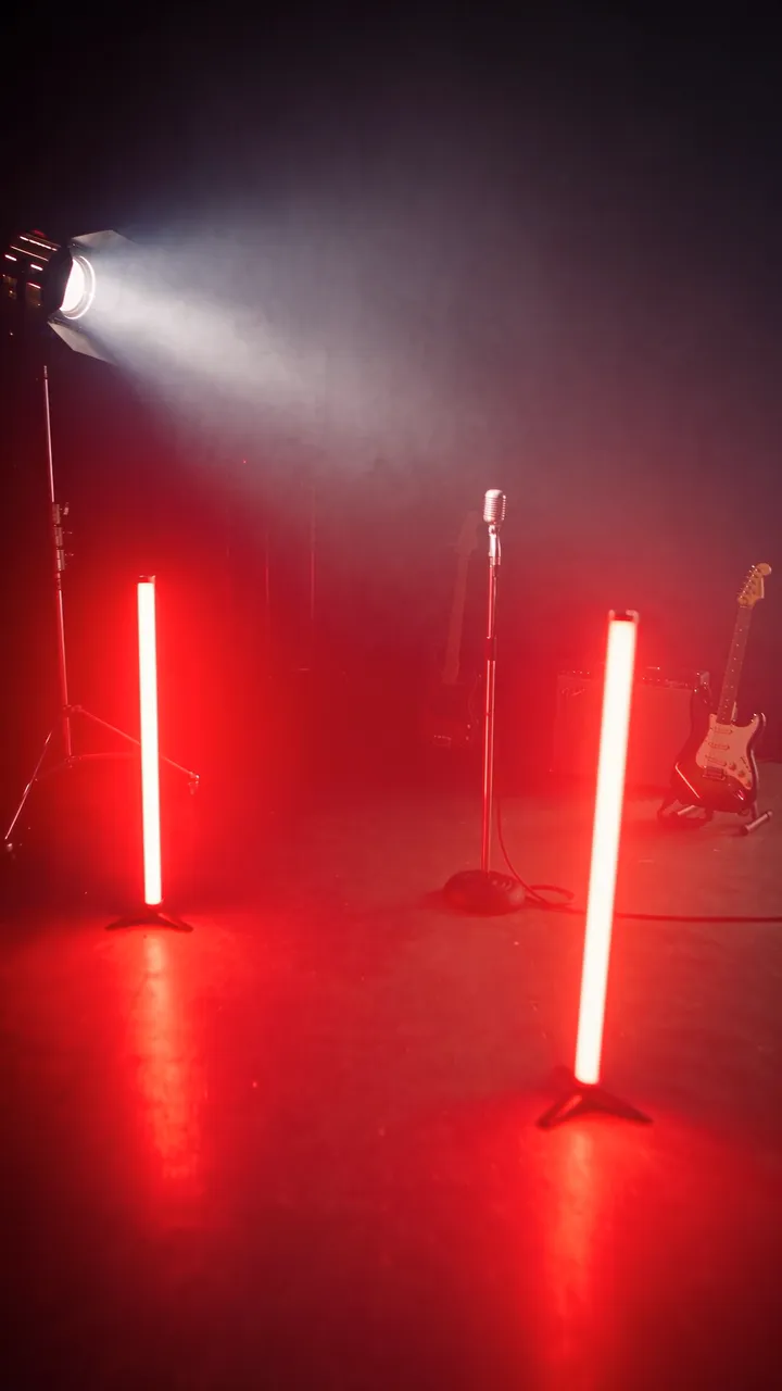 The music video set: a vintage microphone in the haze, two red light tubes, guitars and an amplifier.